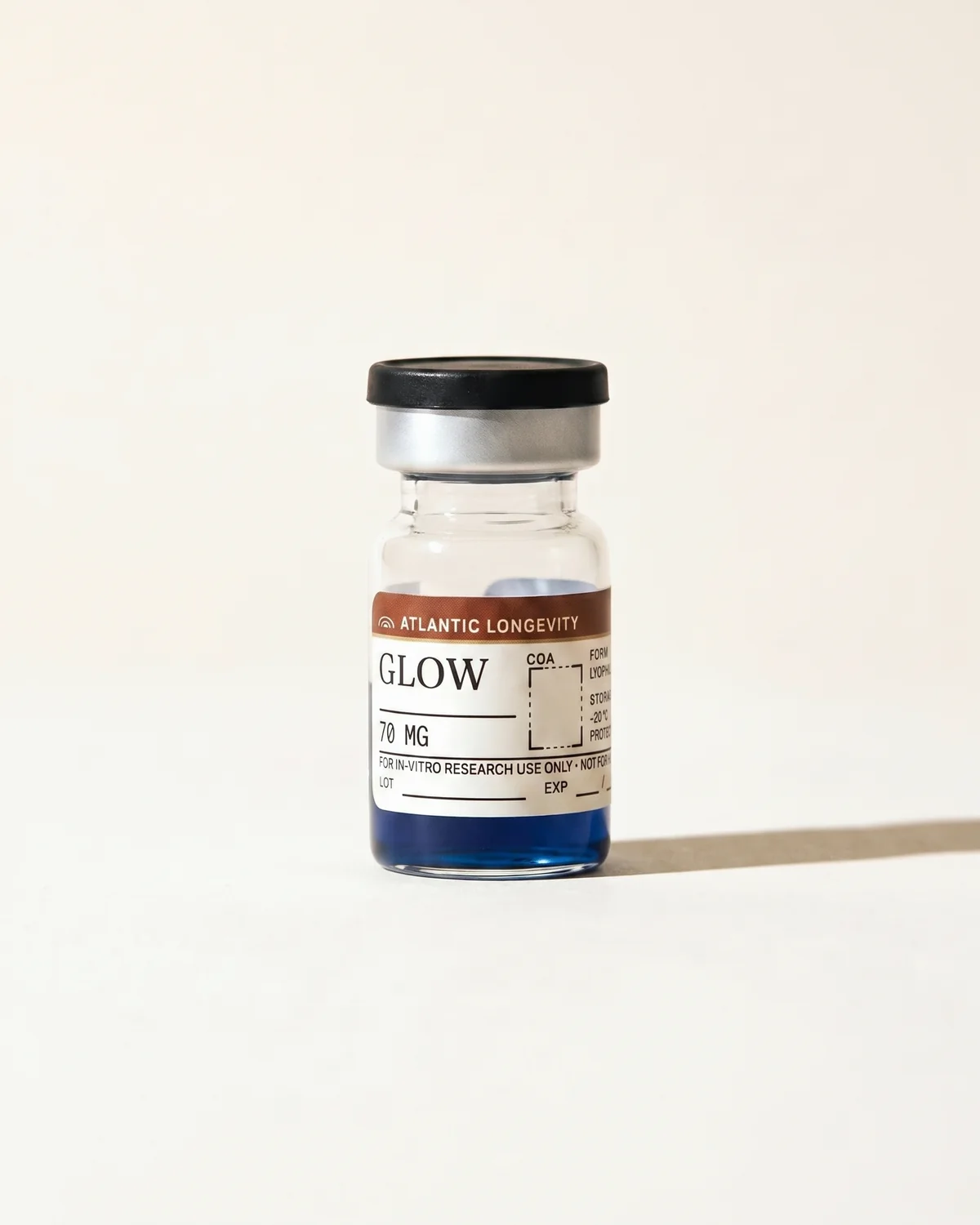 GLOW vial half-filled with copper-blue solution, Atlantic Longevity batch label with lot and expiry write-in fields, on bone paper